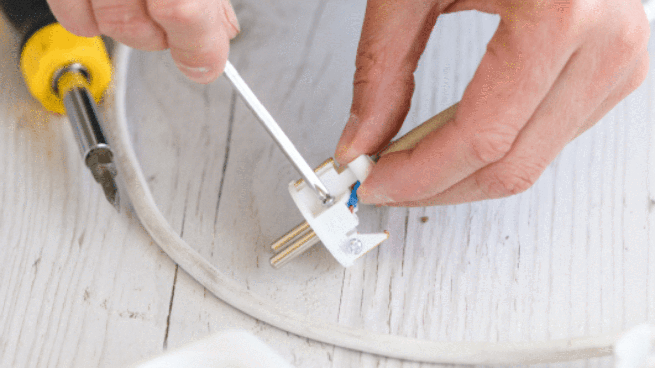 electrician-repair-man-hands-spin-tighten-screws-with-screwdriver-small-plastic-european-extension-plug-cord-power-strip-close-up 1-min