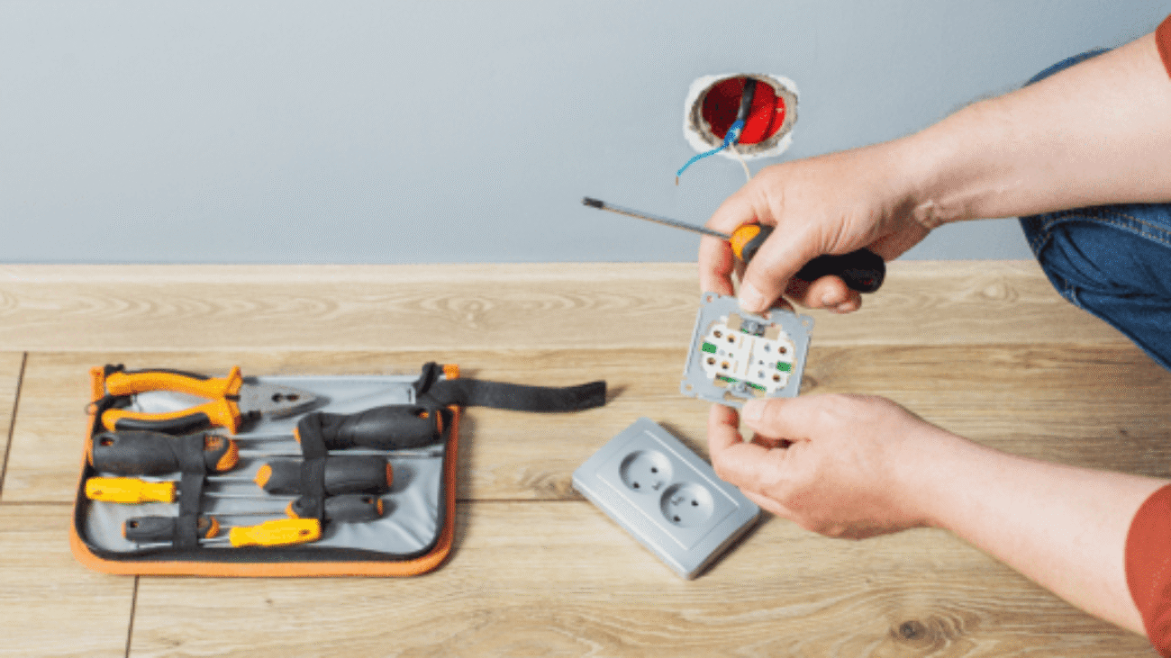 man-installs-electrical-outlet-gray-wall 1-min